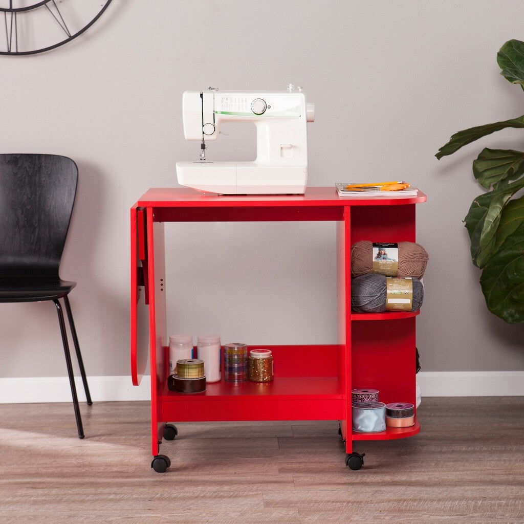 Red expandable rolling sewing table with a white sewing machine and craft supplies